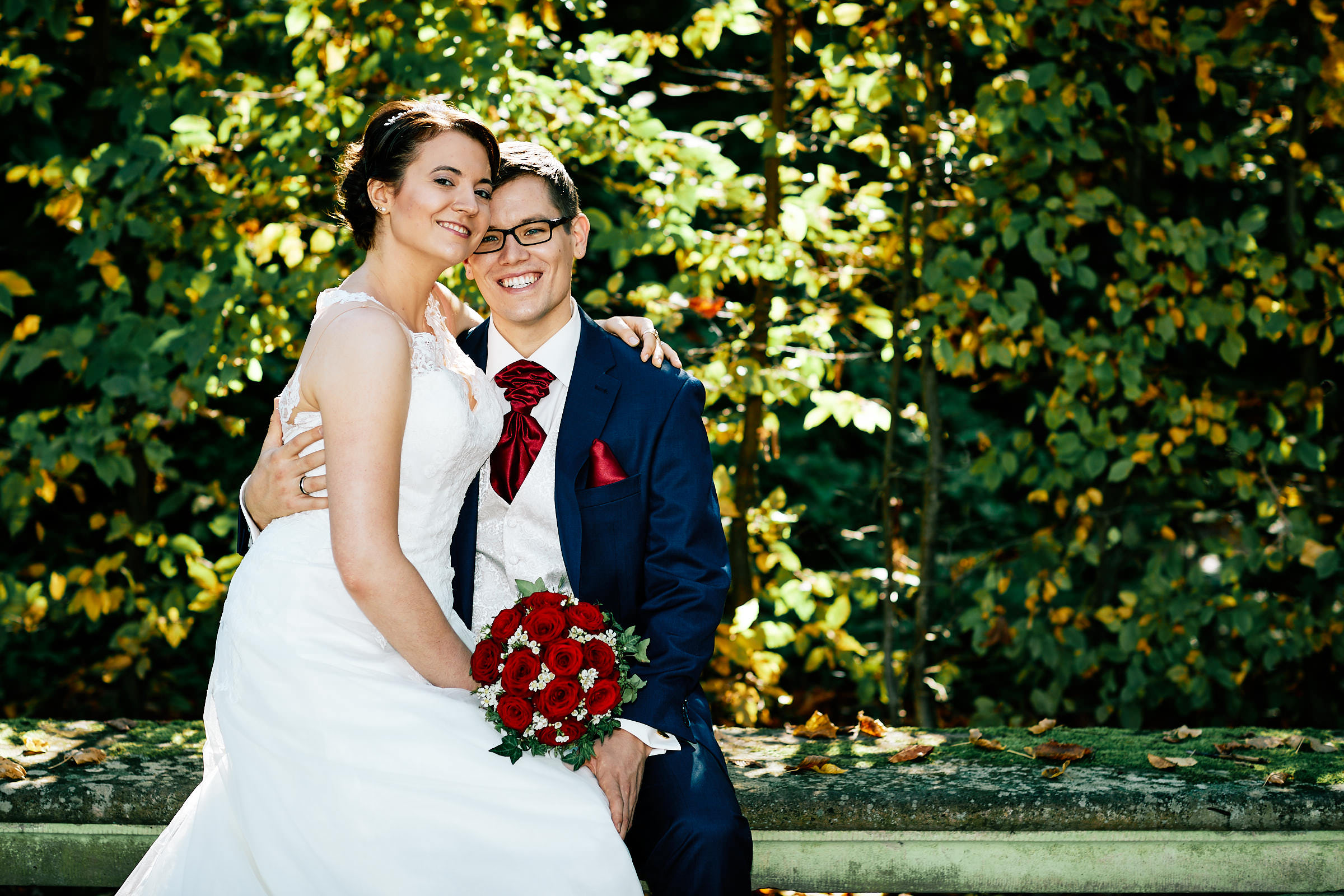 Hochzeitsfotograf Schwetzingen. Die Braut sitzt mit Bräutigam gemeinsam auf einer Parkbank.